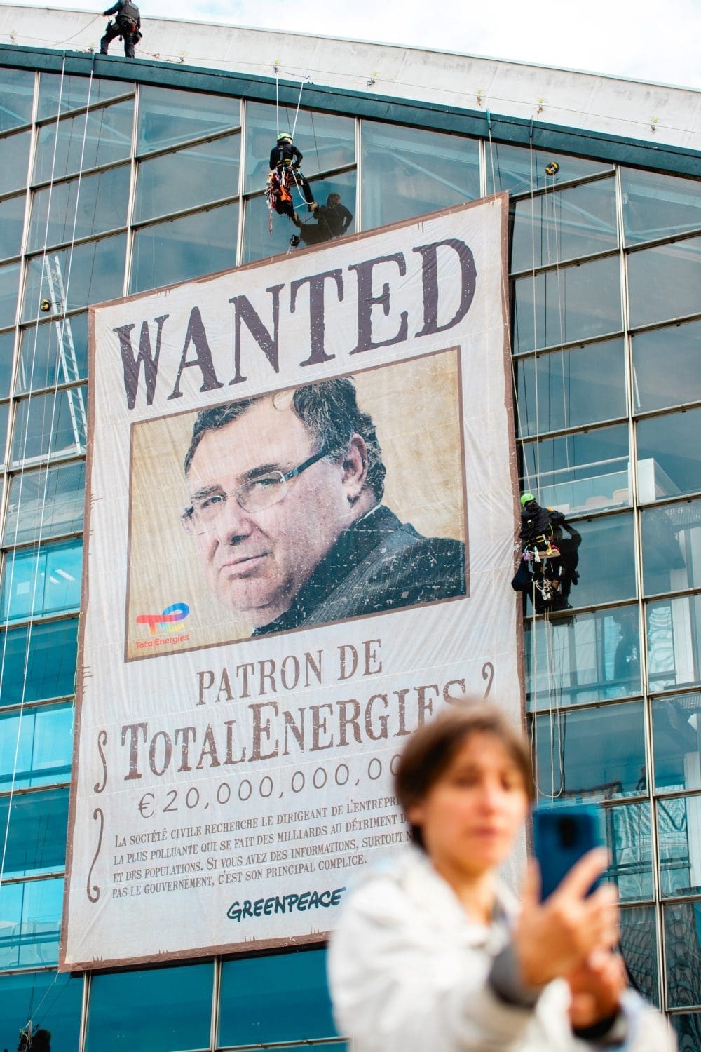"WANTED" banner with Pouyanne's face unfurled on TotalEnergies building.